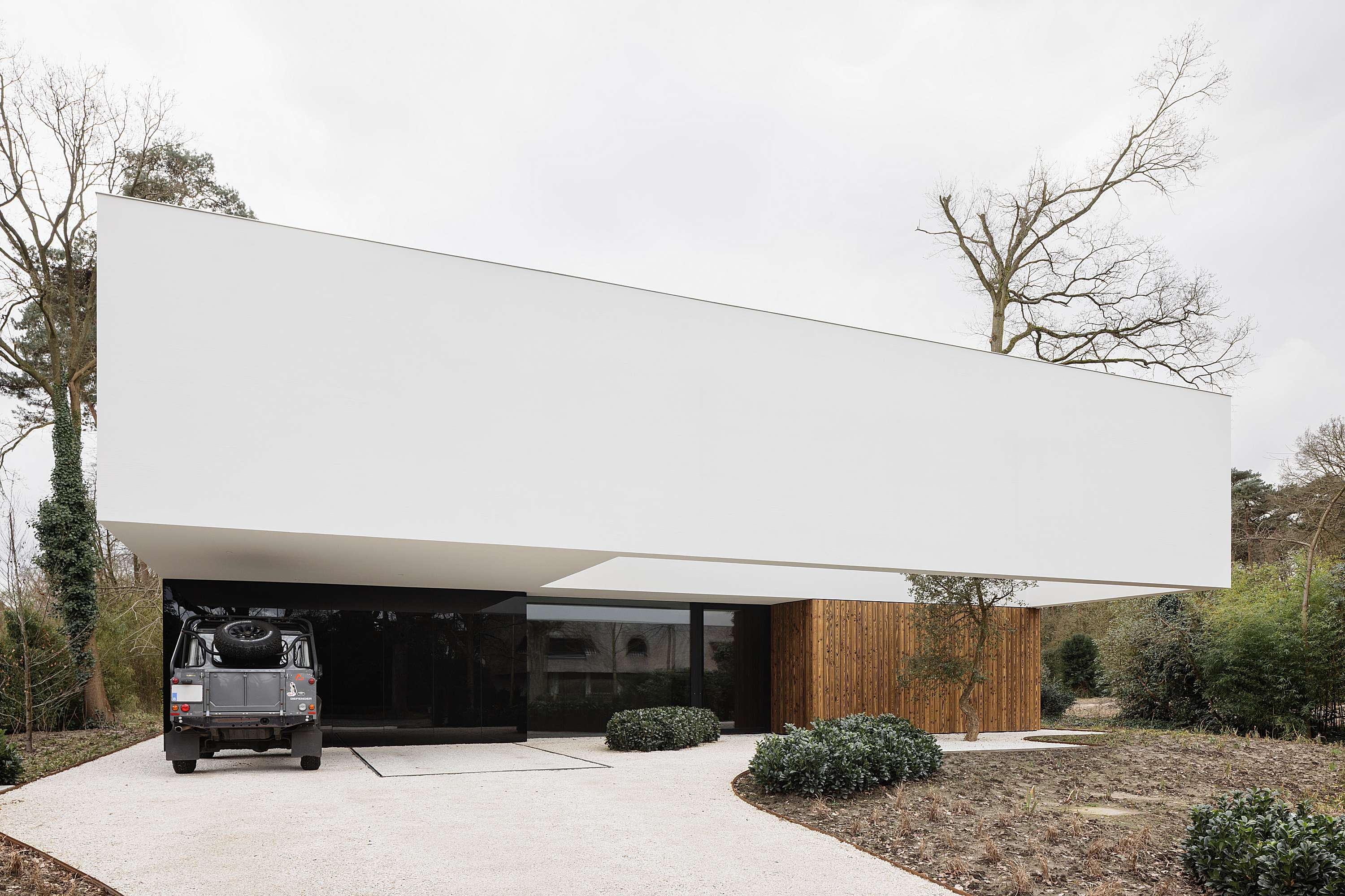 hedendaagse vrijstaande woning met warme accenten frilinglei brasschaat icoon.be architecten brasschaat_minimalistische vrijstaande woning zwevende verdieping zwart glas verbrand hout warm modern